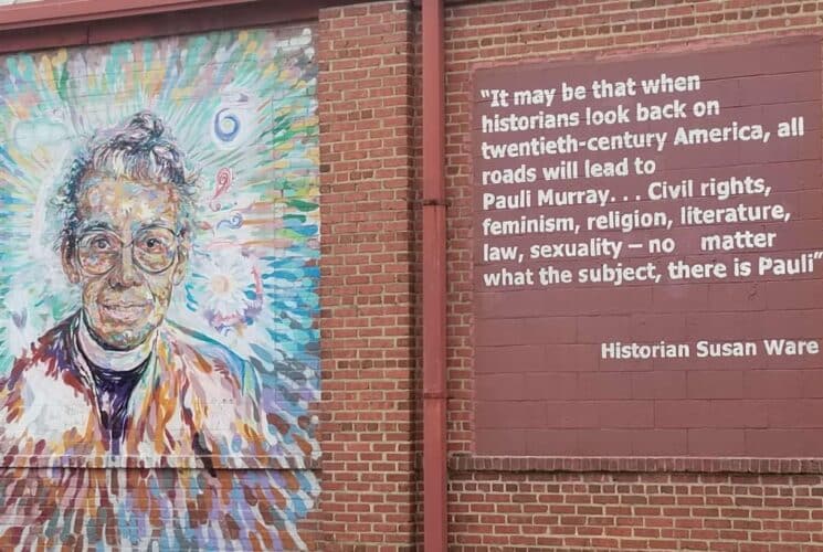 Red brick wall with painting of a woman named Pauli Murray on the left and a historical quote on the right about the woman