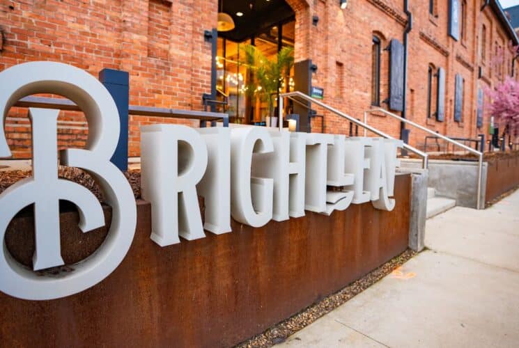 Close up view of white Brightleaf sign in front of red brick building