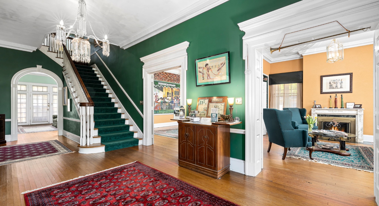 Front entrance with dark green walls, white trim, hardwood flooring, staircase to second floor, and views to multiple rooms