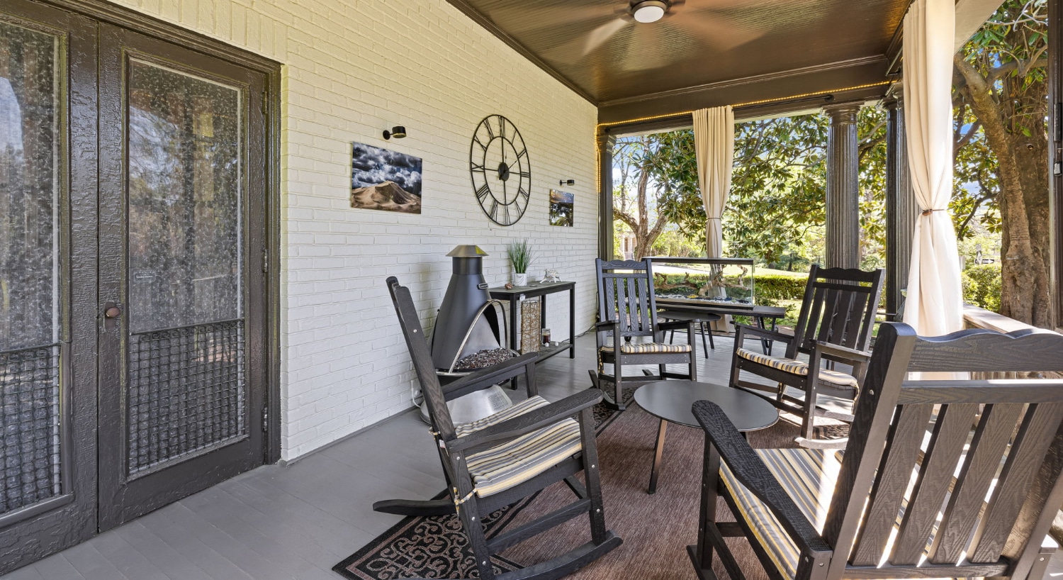 Front porch with dark gray wooden rocking hairs and small table