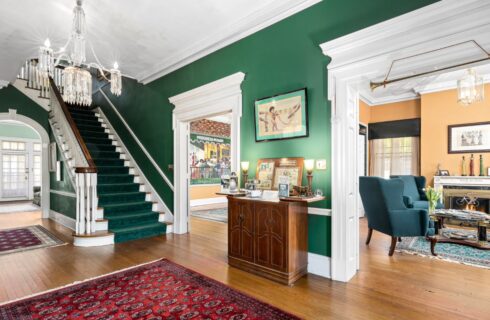 Front entrance with dark green walls, white trim, hardwood flooring, staircase to second floor, and views to multiple rooms