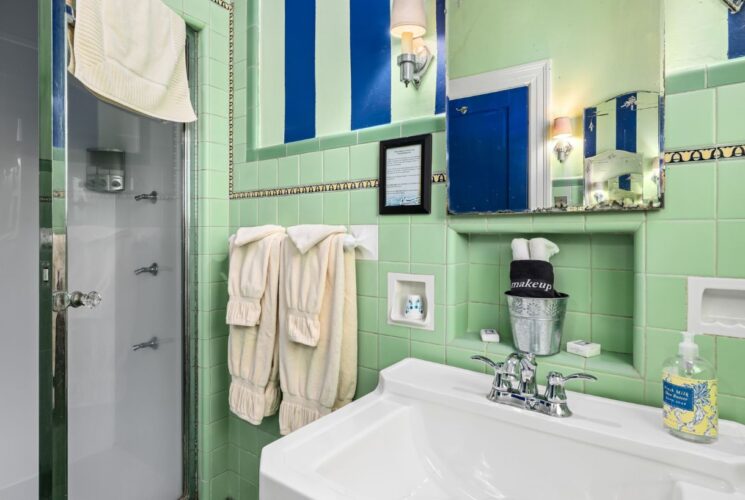 Bathroom with lime green tiling on the walls, white sink, and stand up shower