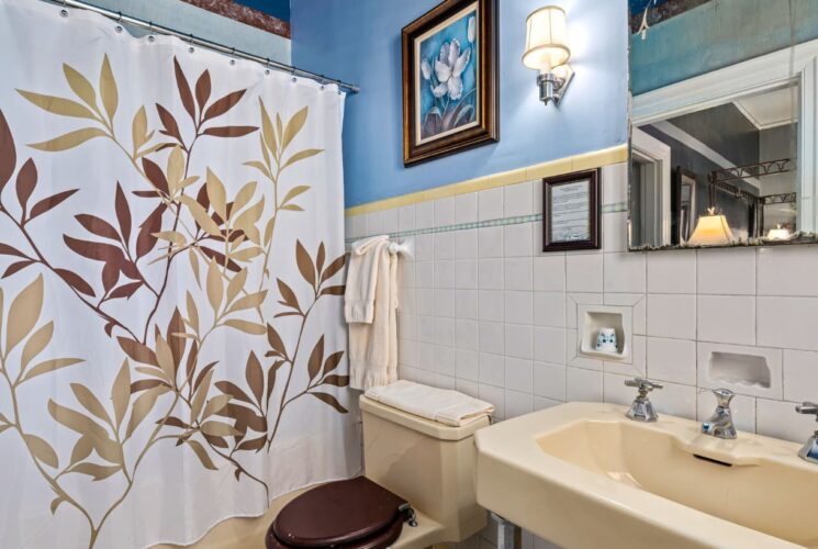 Bathroom with white tile wainscotting and blue walls, almond sink, toilet, and tub/shower combo unit