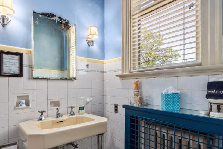 Bathroom with white tile wainscotting and blue walls, almond sink, blue radiator cover, and window