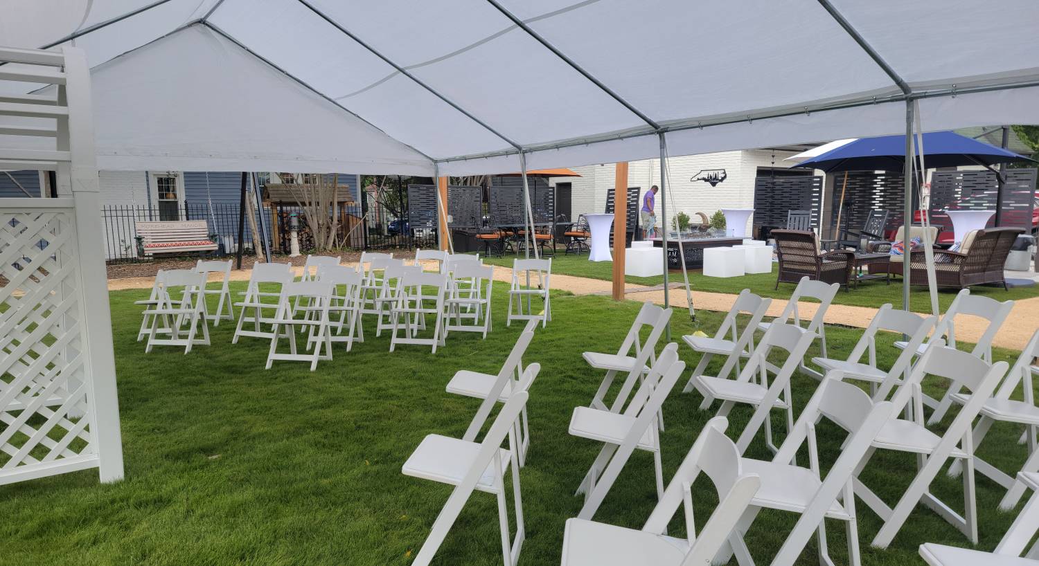 Large white tent set up on green lawn with multiple white chairs set up for an event