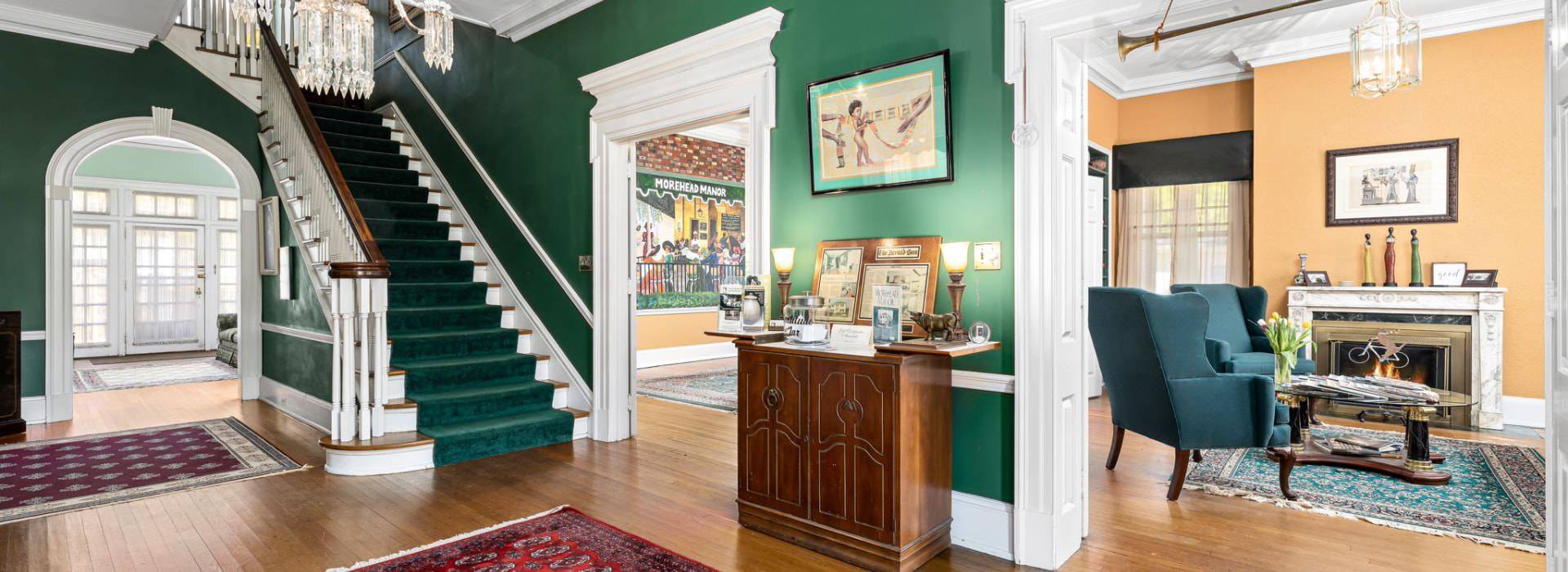 Front entrance with dark green walls, white trim, hardwood flooring, staircase to second floor, and views to multiple rooms